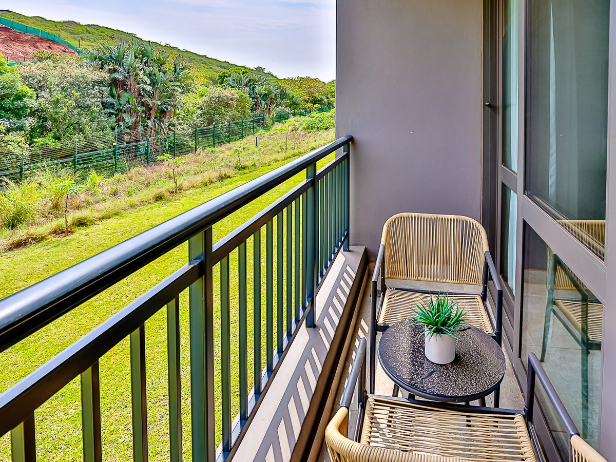 Balcony with two chairs looking over lawn and coastal forest
