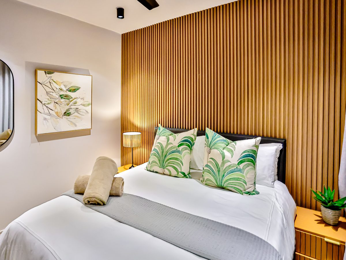 Main bedroom with a queen bed and timber feature wall